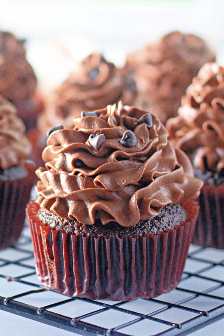 Frosted chocolate cupcake topped with mini chocolate chips on a cooling rack