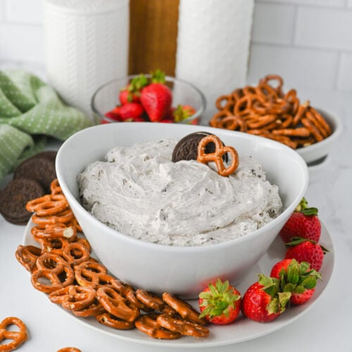 Creamy Oreo dip surrounded by pretzels, strawberries, and milk