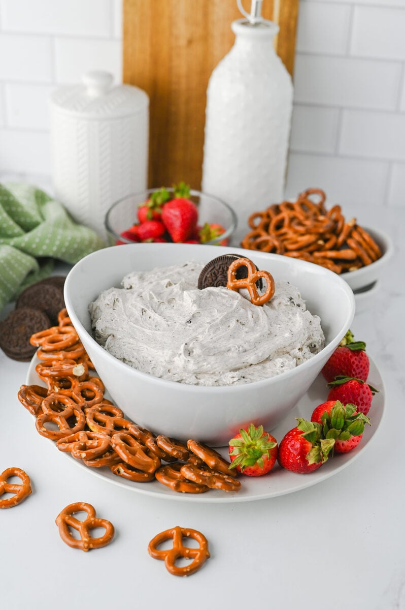 Creamy Oreo dip surrounded by pretzels, strawberries, and milk