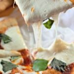 Fried pizza with a mozzarella cheese pull and fresh basil