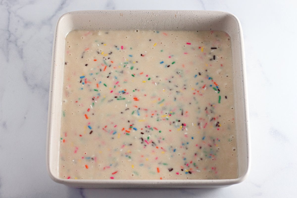 Funfetti cake batter poured into a square baking pan