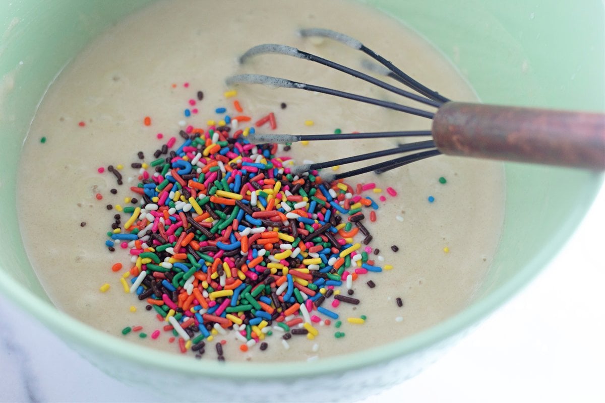 Folding rainbow sprinkles into the cake batter