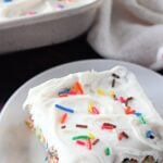 Funfetti crazy cake topped with white frosting and rainbow sprinkles