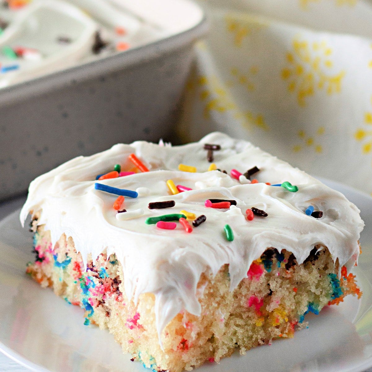 Close-up of a frosted funfetti crazy cake slice topped with sprinkles