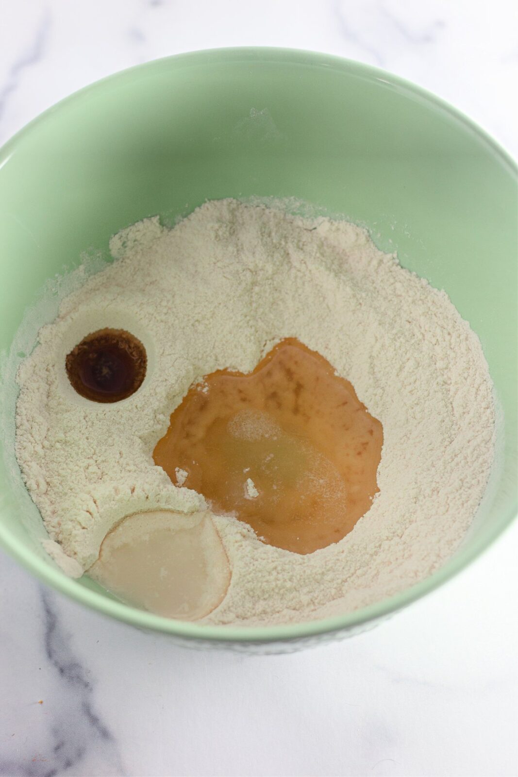 Oil, vinegar, and vanilla poured into wells in the dry ingredients