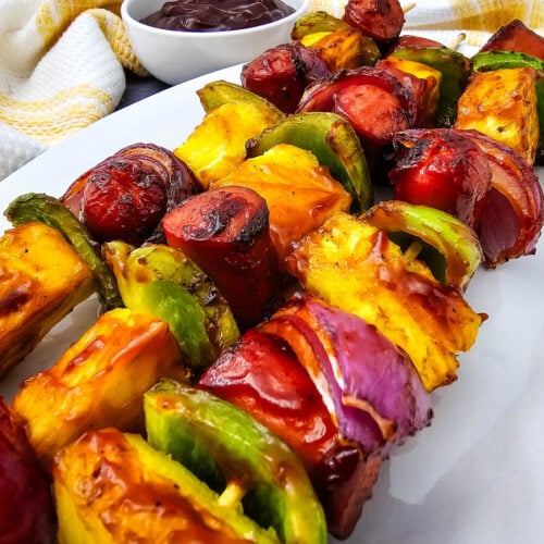 Overhead view of grilled hot dog kabobs on a white platter
