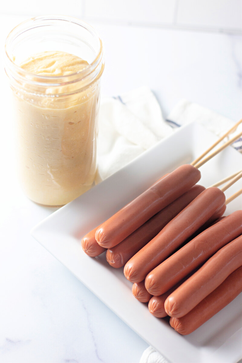 Corn dog batter poured into a tall glass for dipping