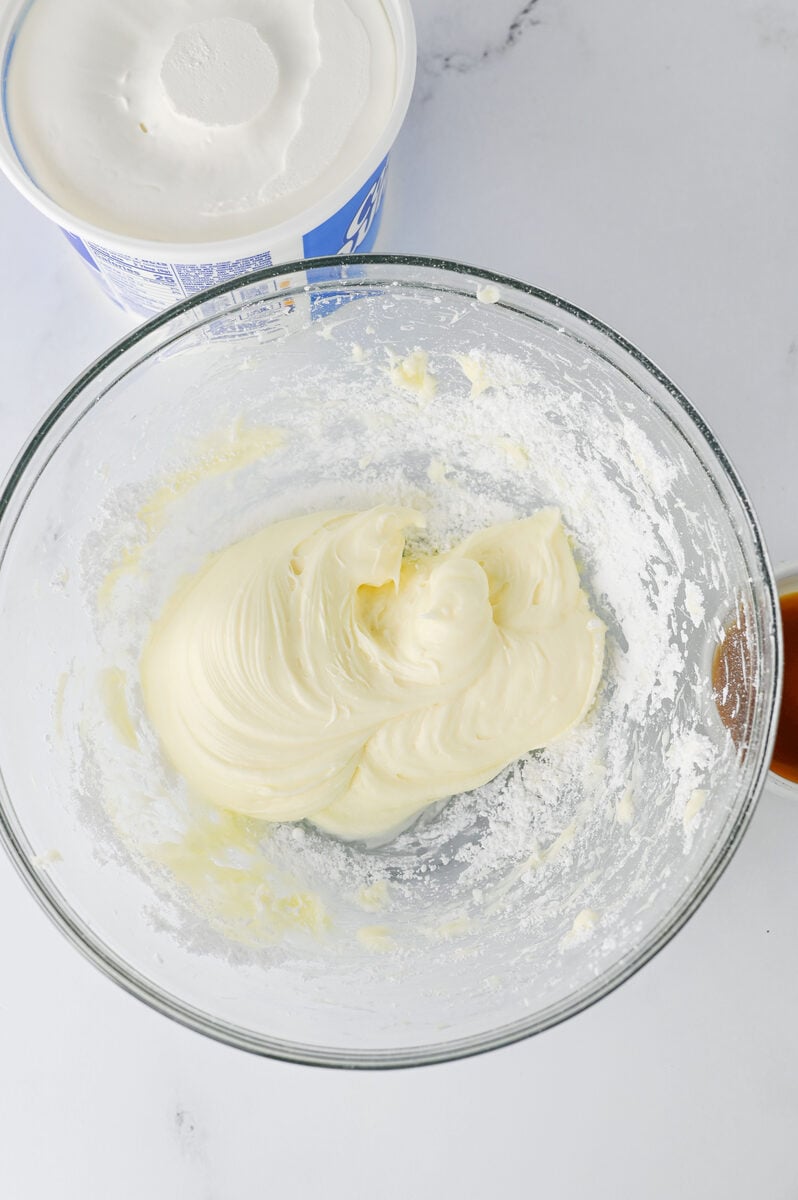 Beating cream cheese and powdered sugar in a glass bowl