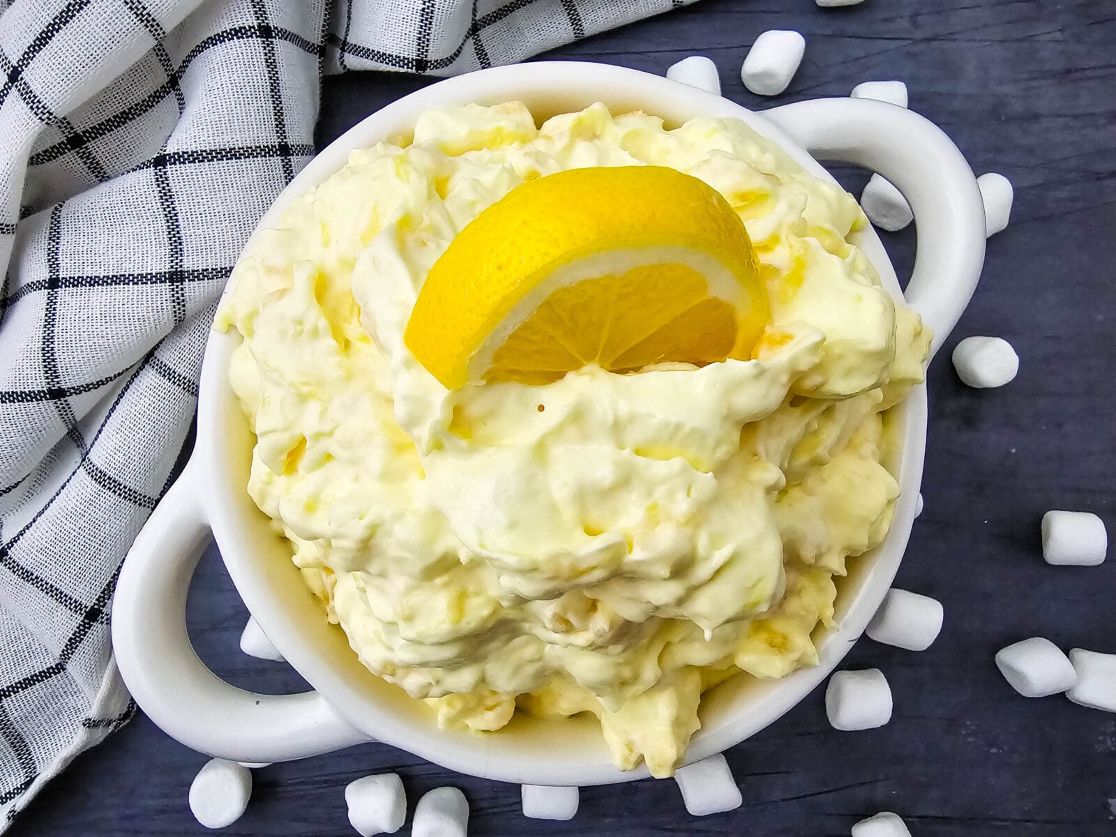 Lemon fluff salad in a glass bowl topped with coconut and lemon slices