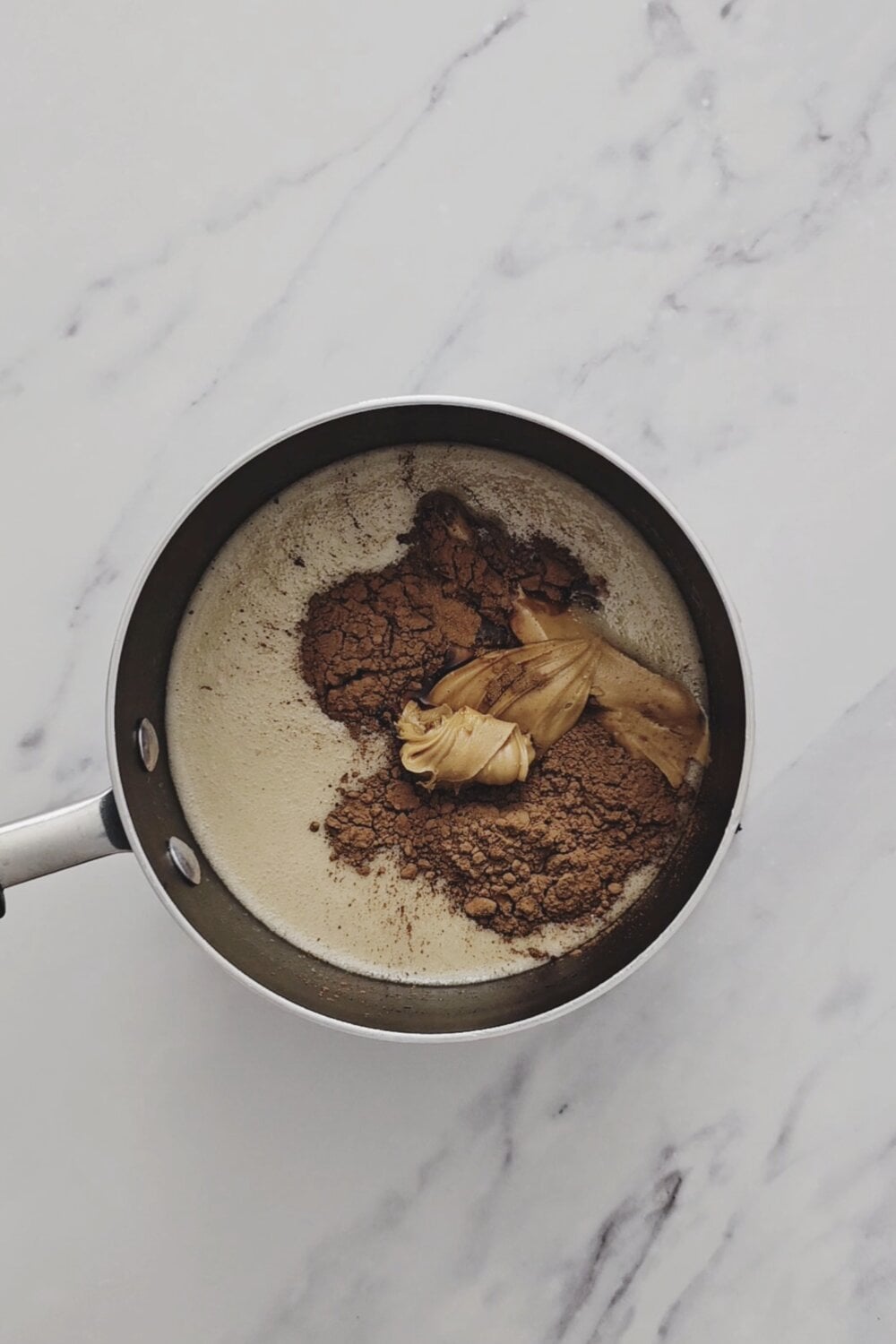Cocoa powder and peanut butter added to the hot sugar mixture in the saucepan.