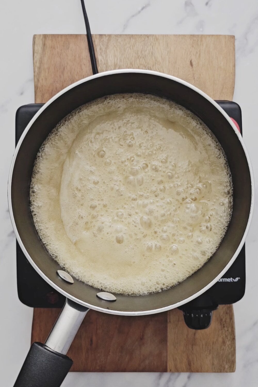 Sugar, butter, and milk mixture at a rolling boil in a saucepan.