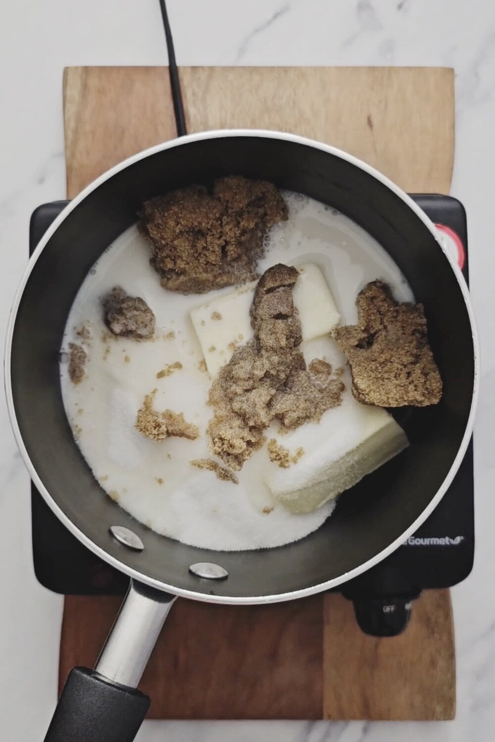 Butter, white sugar, brown sugar, and milk in a saucepan before melting.