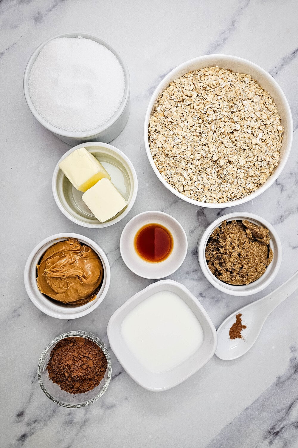 Ingredients for no-bake cookies: oats, sugars, butter, milk, cocoa powder, peanut butter, vanilla, and cinnamon.