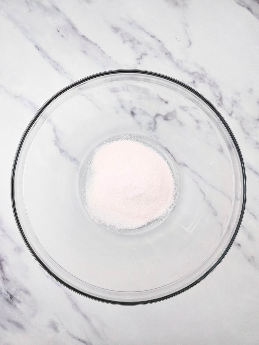 Orange gelatin powder in a glass mixing bowl