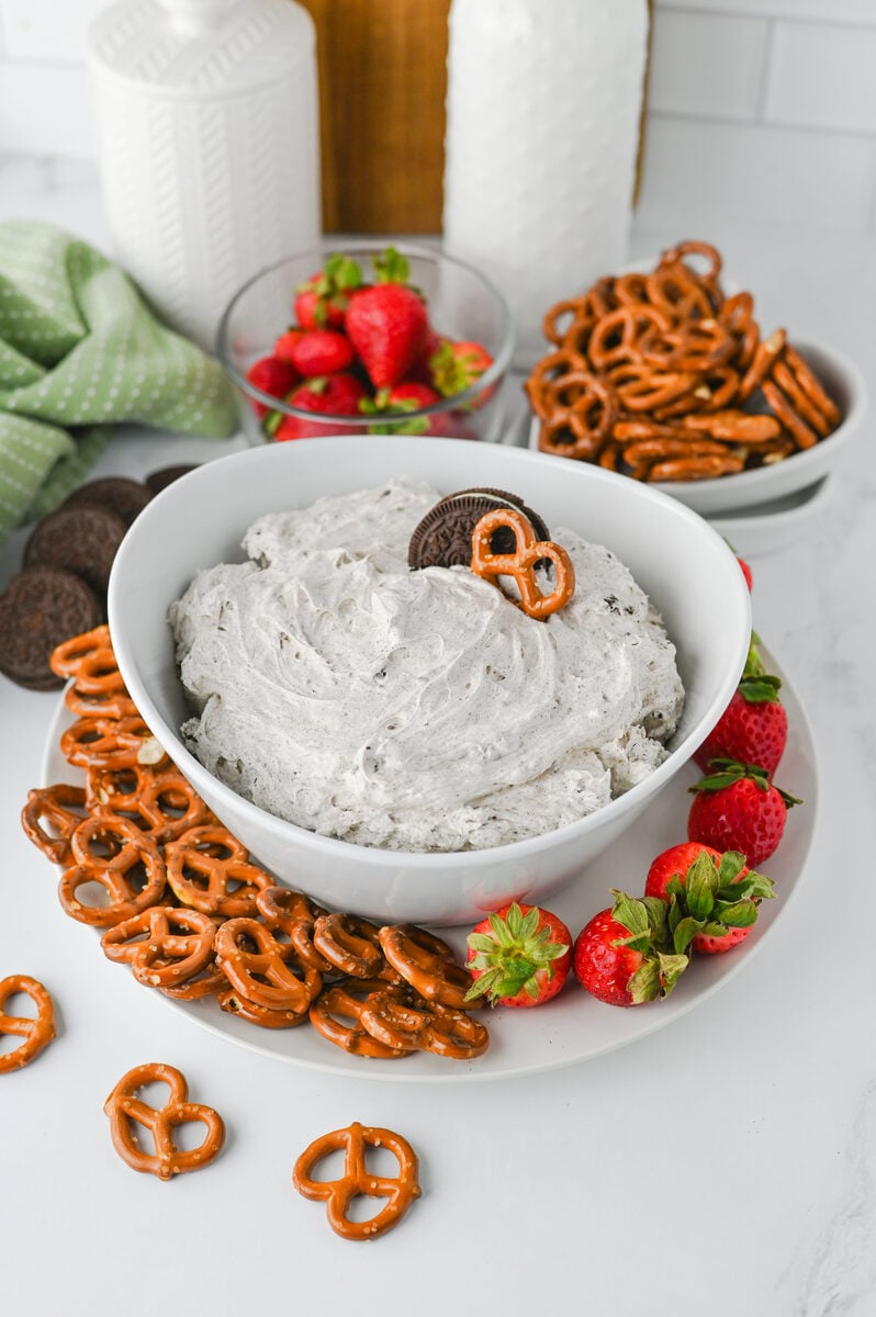 Oreo dip in a white bowl with a pretzel dipped in