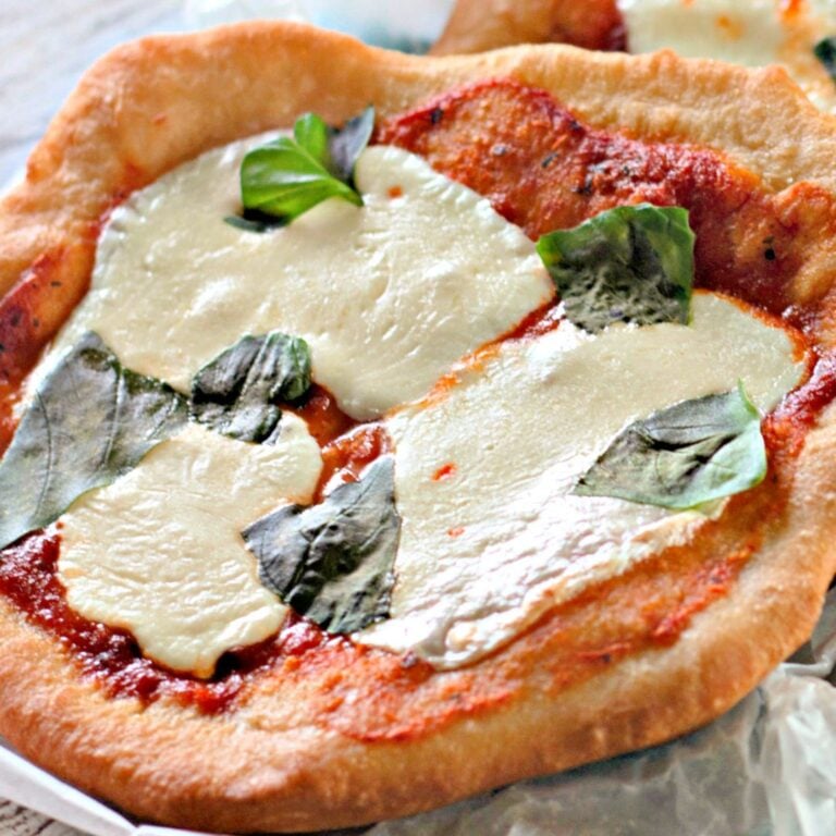 Close up of a golden brown fried pizza crust topping with mozzarella and basil