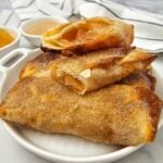 Crispy air fryer apple pie filling egg rolls stacked on a plate