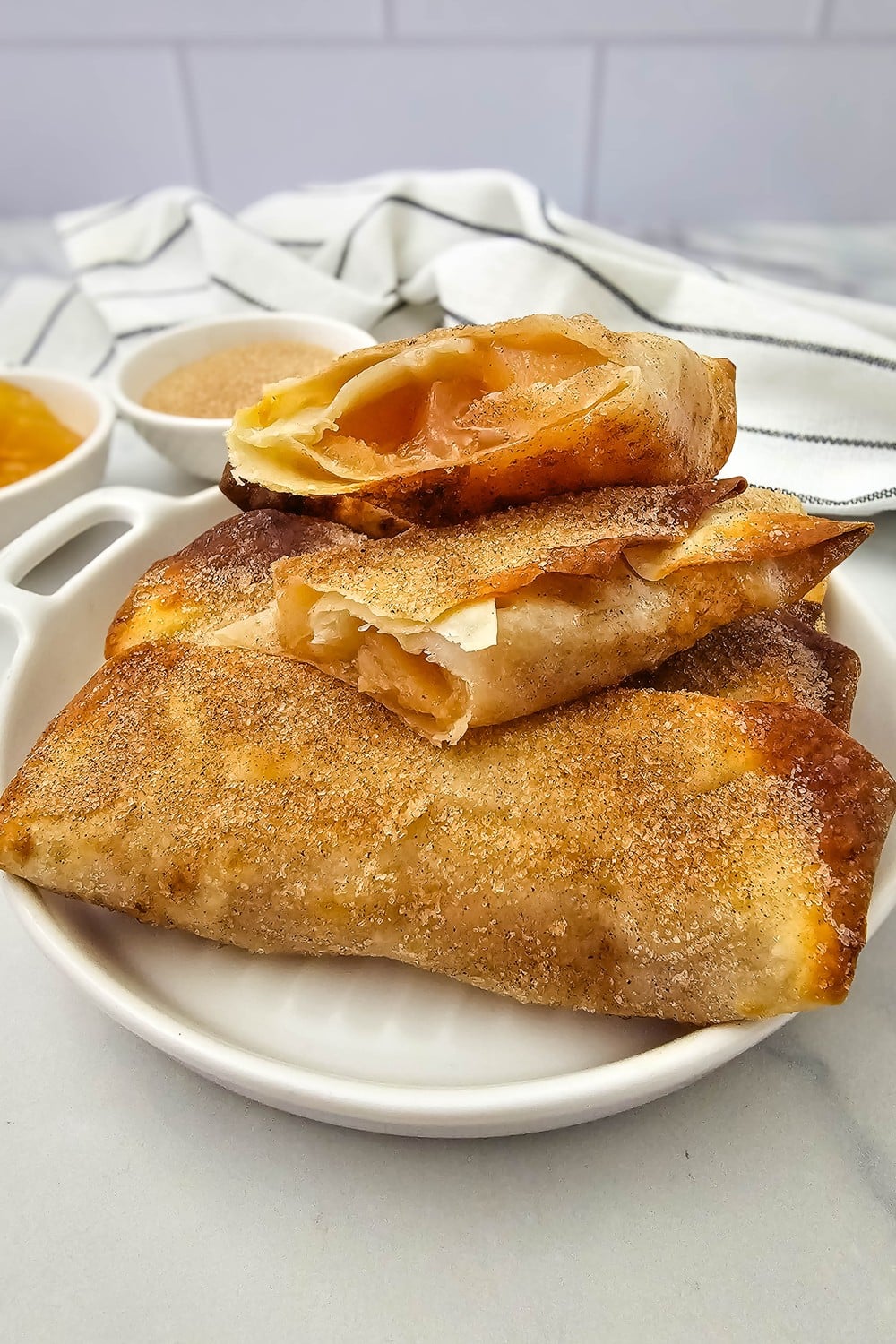 Crispy air fryer apple pie filling egg rolls stacked on a plate