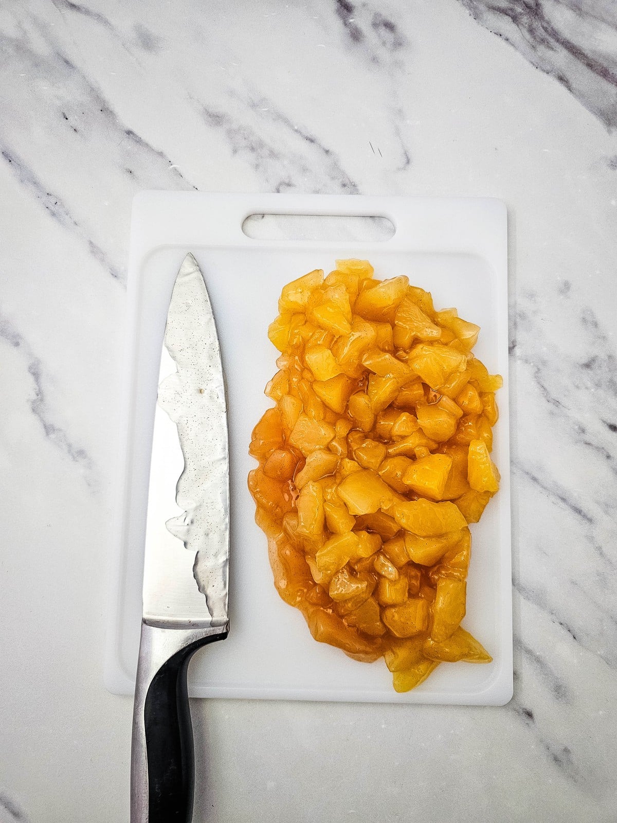 Apple pie filling chopped into small pieces on a cutting board with a knife