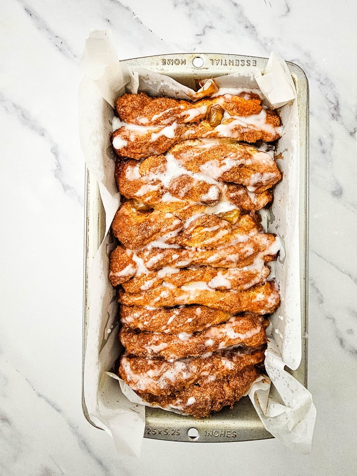 Powdered sugar glaze drizzled over the baked apple cinnamon biscuit loaf