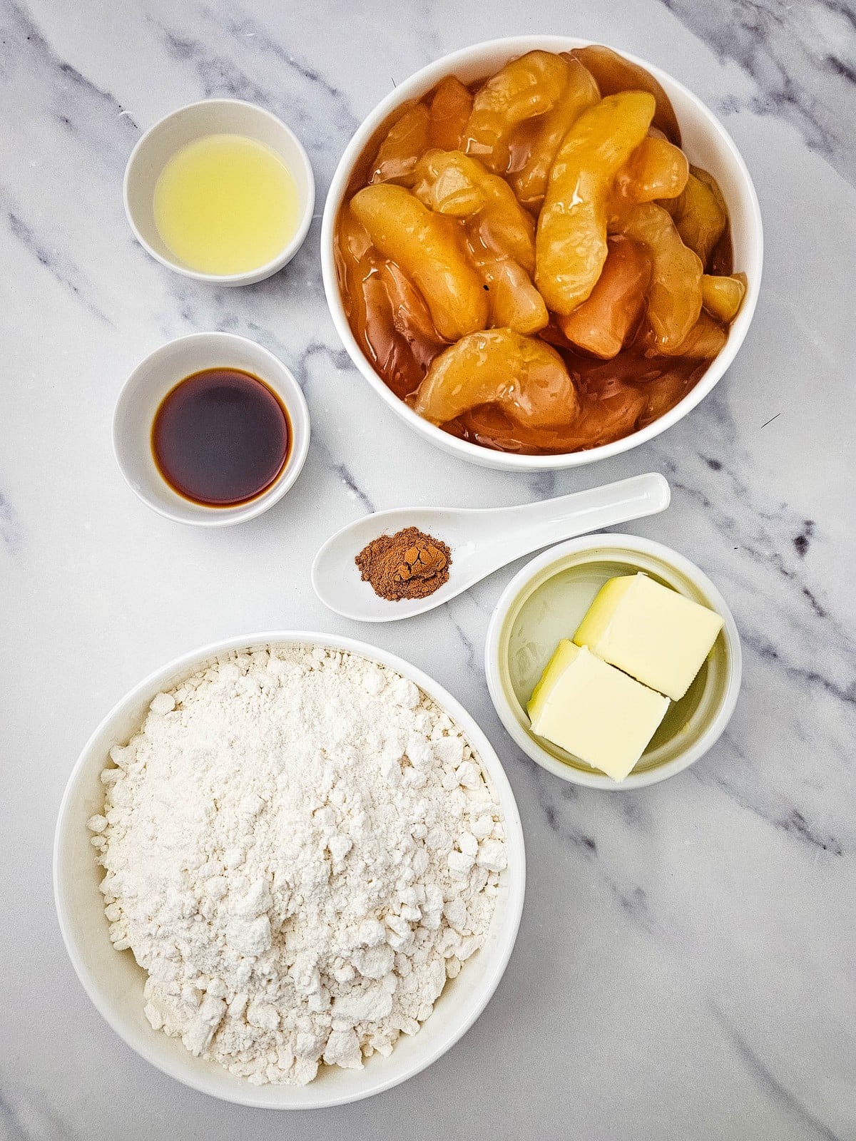 Ingredients for apple cobbler: apple pie filling, butter cake mix, butter, vanilla, cinnamon and lemon juice