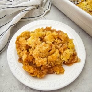 A scoop of apple cobbler showing golden cake topping over apple filling