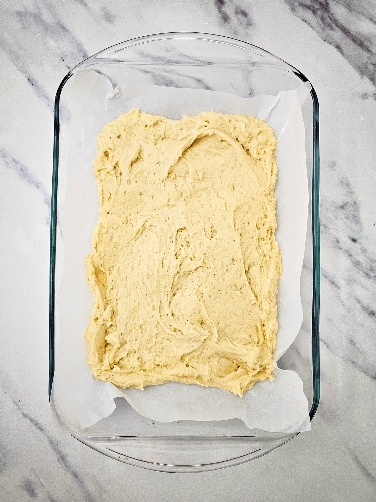 Coffee cake batter spread in a parchment-lined baking dish