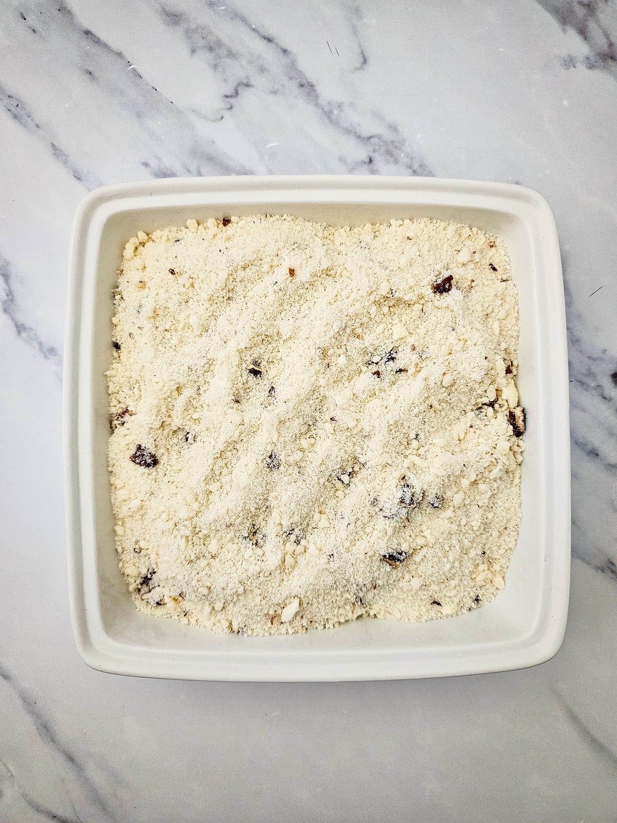 Crumble topping spread over apple pie filling in the baking dish