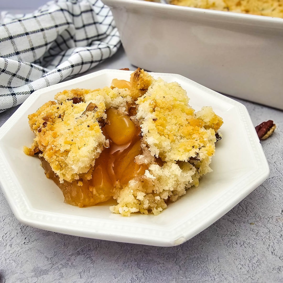A serving of apple crisp with buttery pecan crumble and apple pie filling in a white bowl