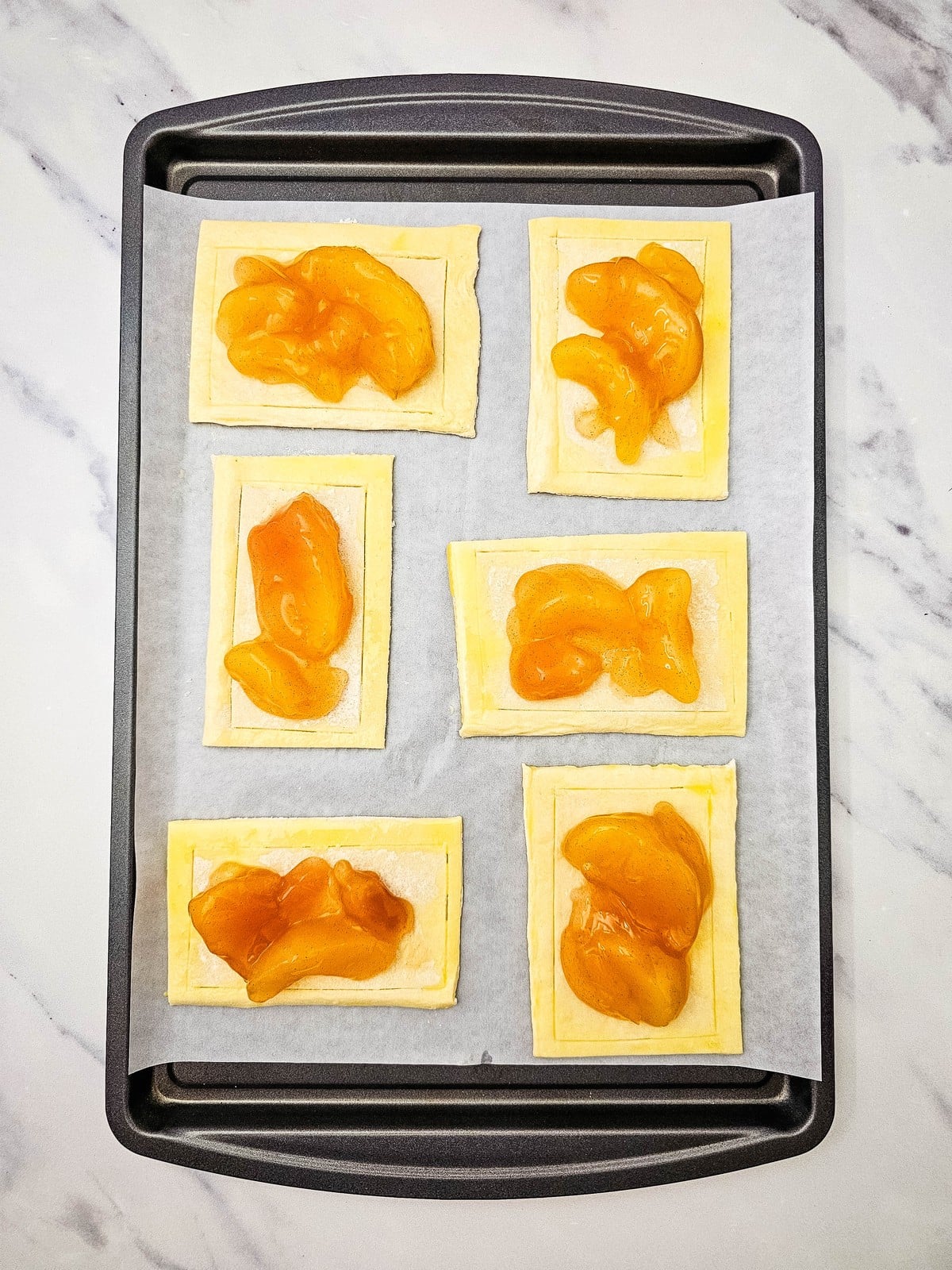 Apple pie filling spooned into the centers of scored puff pastry rectangles