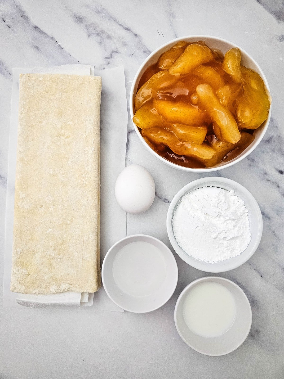 Ingredients for apple danish: puff pastry sheets, apple pie filling, egg, powdered sugar and milk