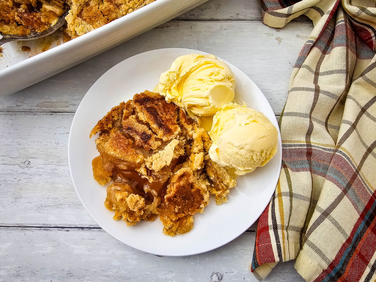 Serving of warm apple dump cake with two scoops of vanilla ice cream