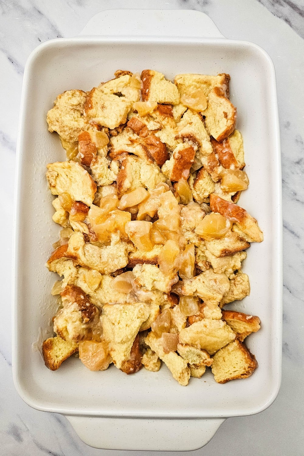 Apple pie bread pudding in a white 9x13 baking dish ready for the oven