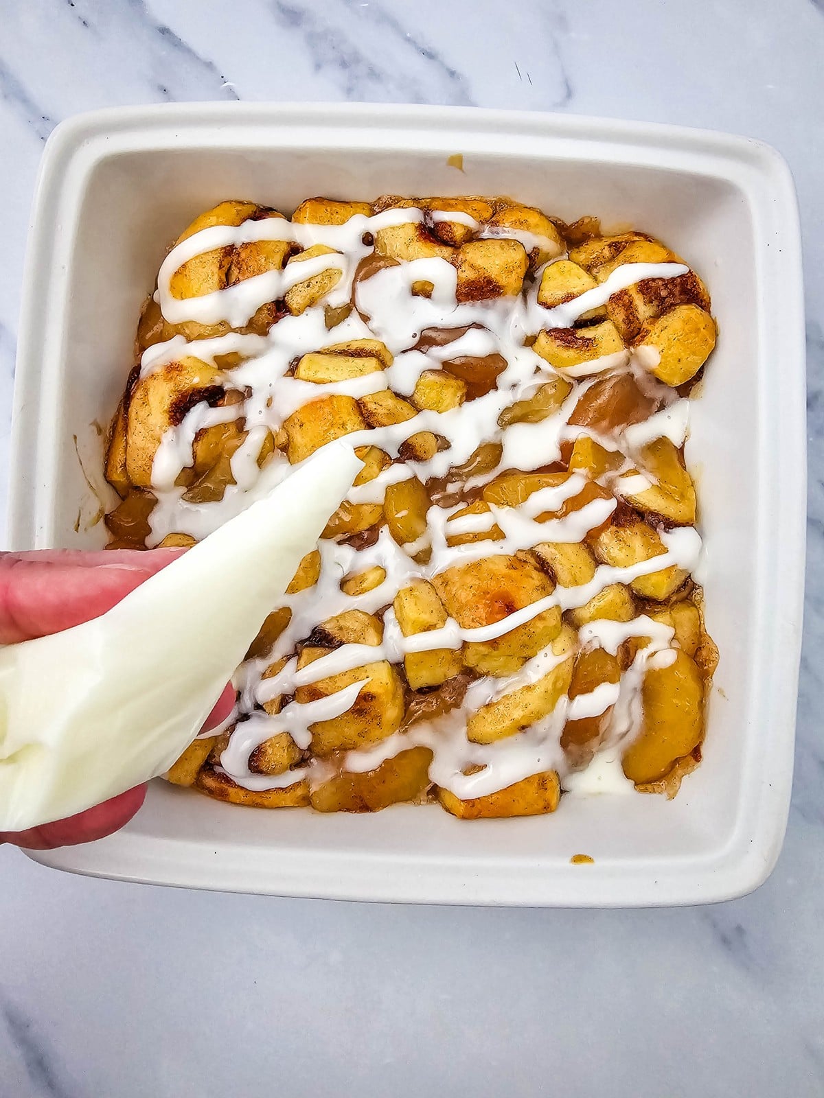 Drizzling the included icing over the baked apple pie cinnamon rolls