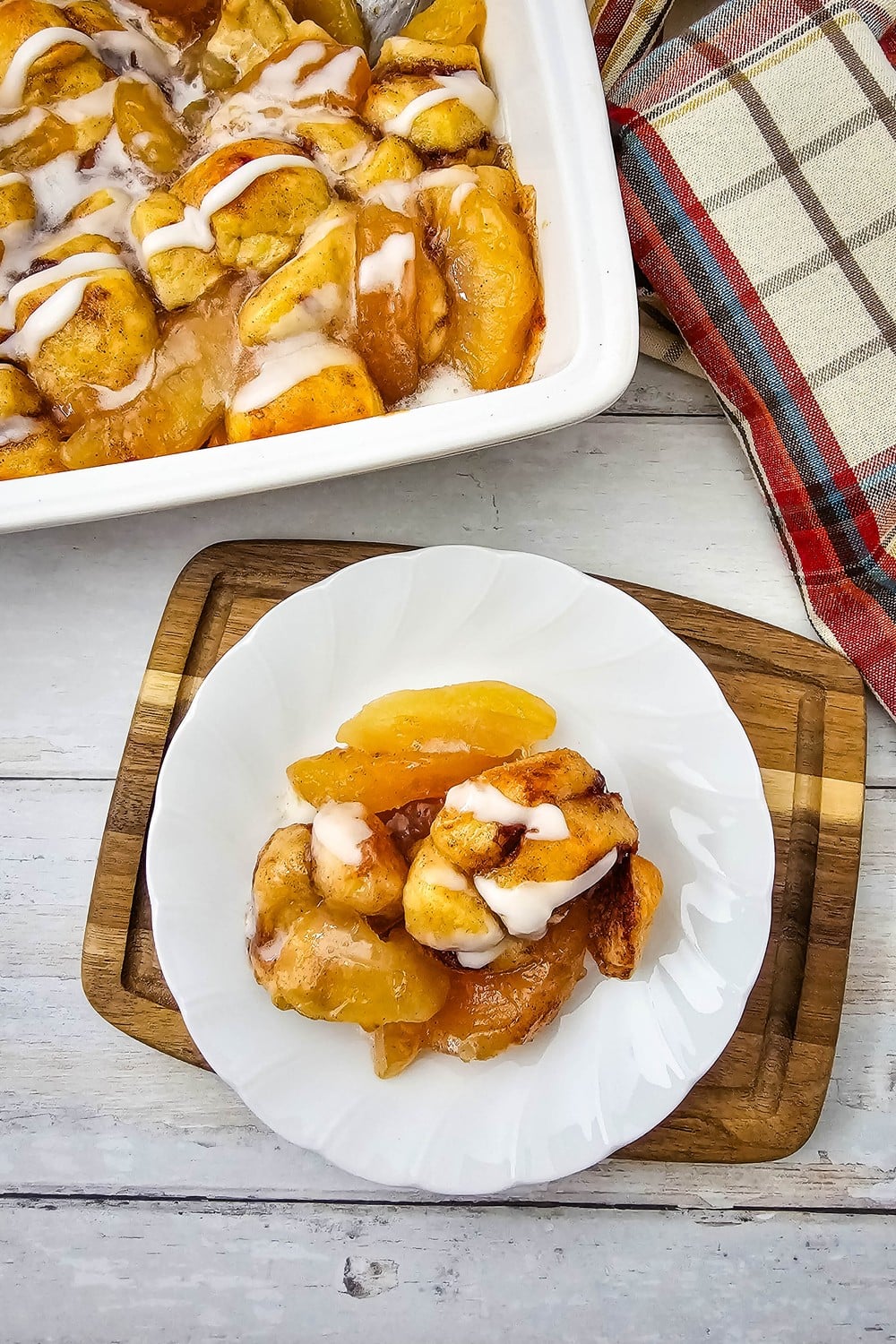Apple pie cinnamon rolls in a square baking dish with a plated serving