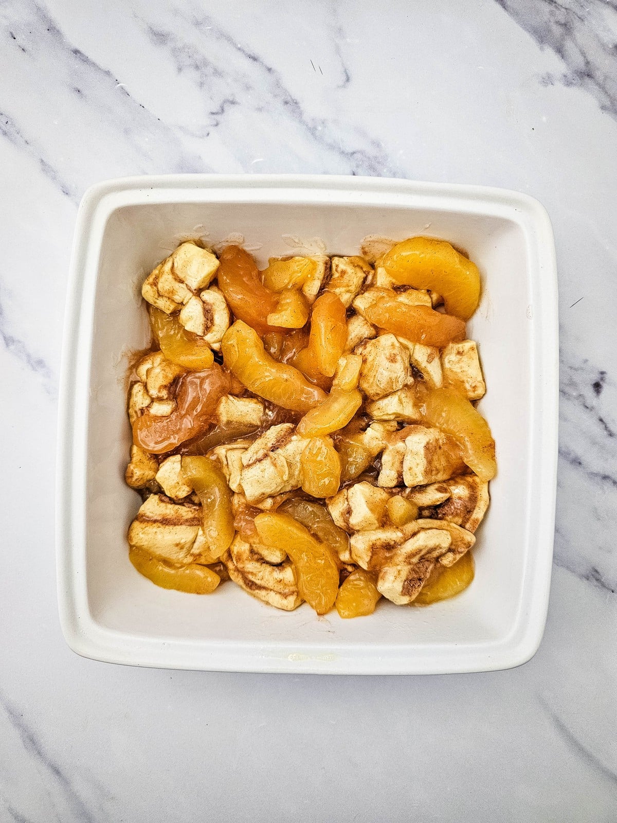 Cinnamon roll and apple pie filling mixture spread in a greased square baking dish
