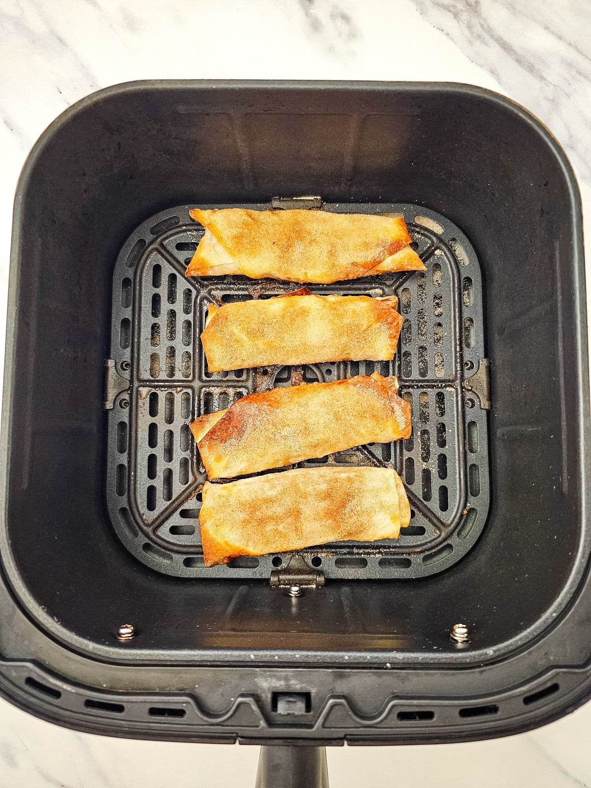 Golden crispy apple pie egg rolls in the air fryer basket