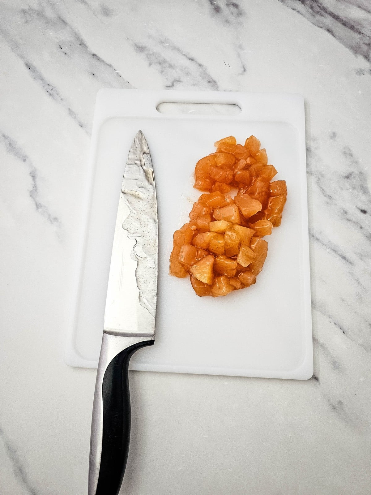 Apple pie filling chopped into small pieces on a cutting board