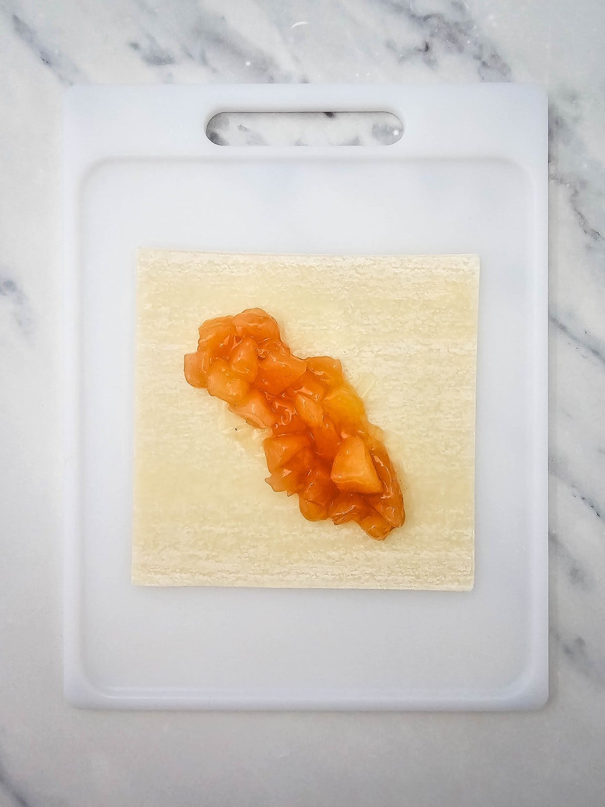Chopped apple pie filling in the center of an egg roll wrapper