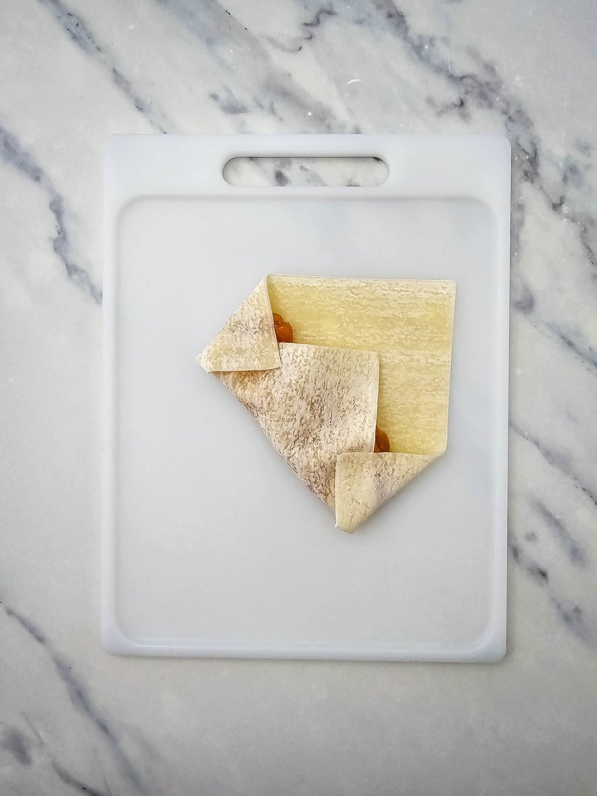 Egg roll wrapper sides folded in before rolling