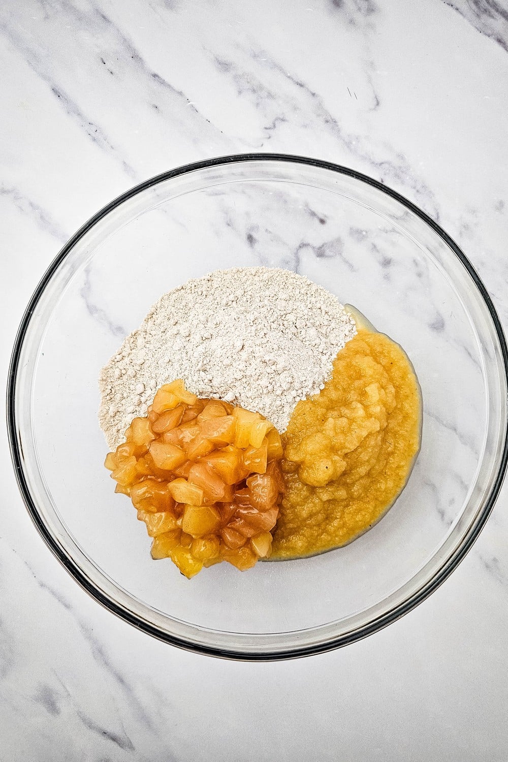 Spice cake mix, applesauce and chopped apple pie filling in a glass mixing bowl