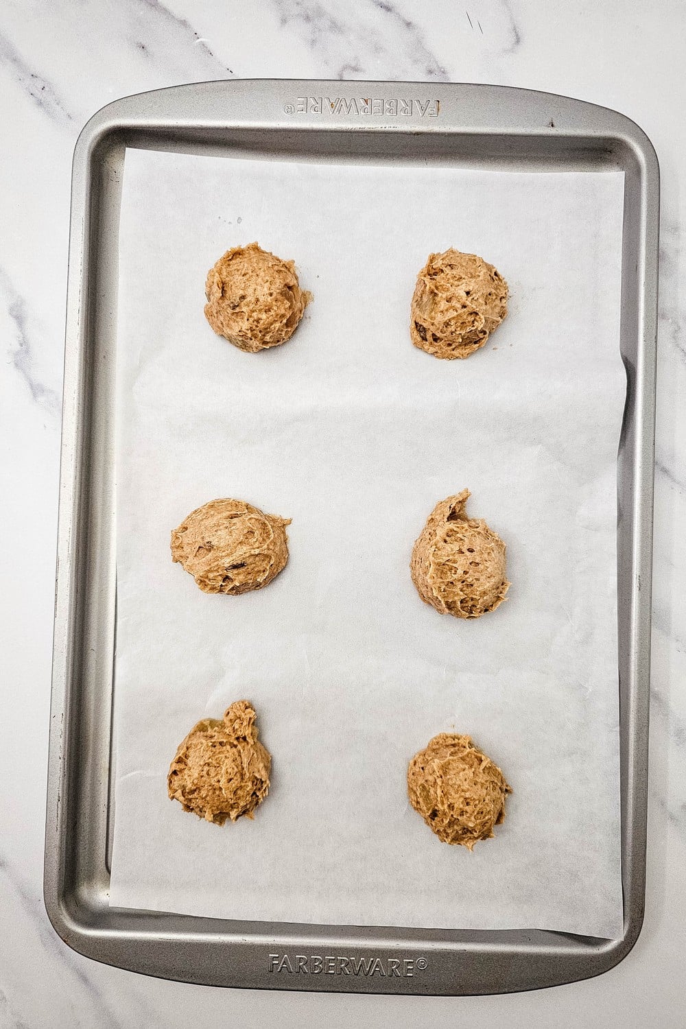 Cookie dough scoops spaced on a parchment lined baking sheet