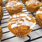 Apple pie filling muffins with a powdered sugar glaze on a cooling rack