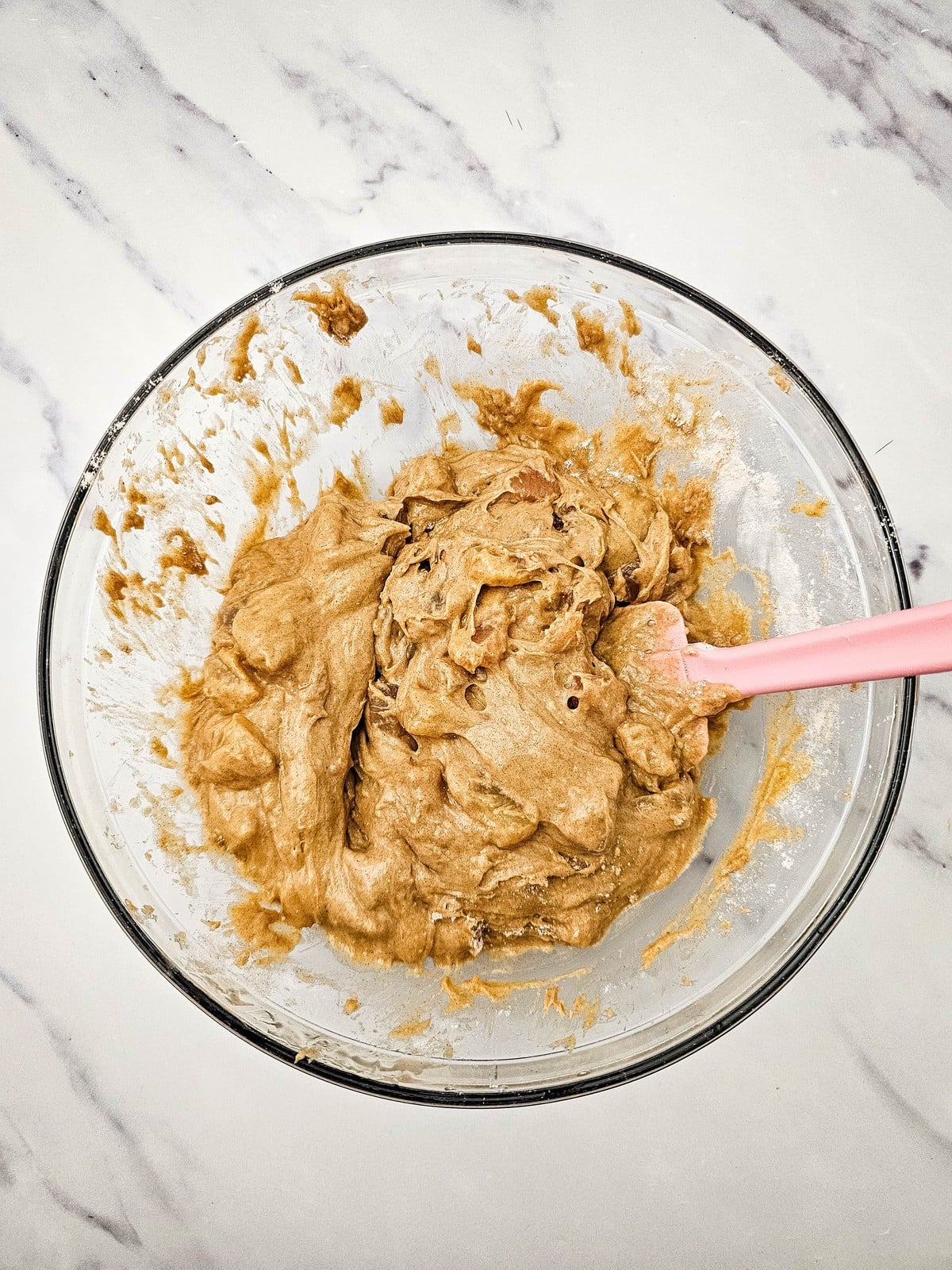 Thick apple muffin batter in a glass bowl