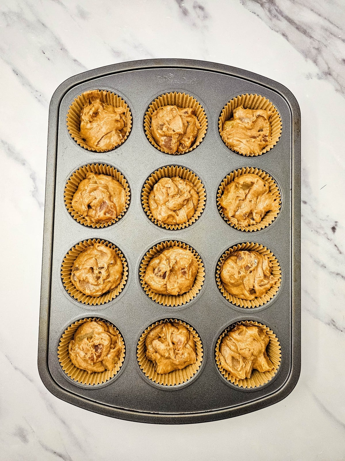 Muffin tin filled with apple pie filling muffin batter