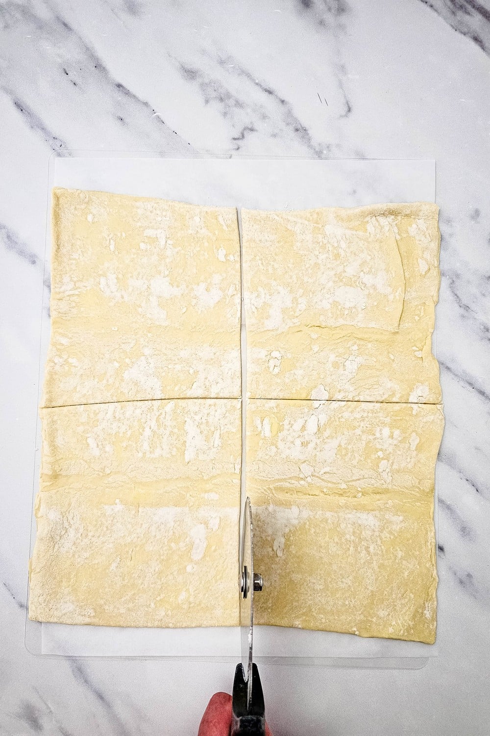 Cutting puff pastry into four squares with a pizza cutter