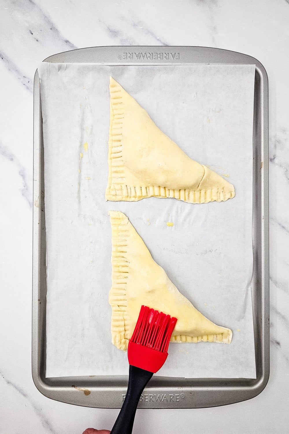Brushing egg wash over folded apple turnovers