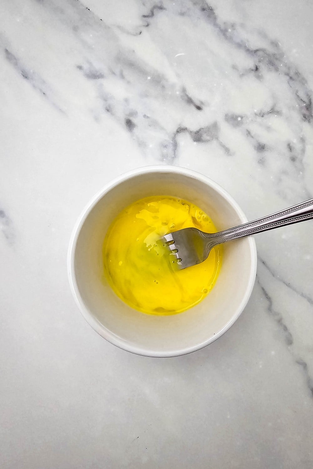 Egg and water whisked together in a small bowl for egg wash