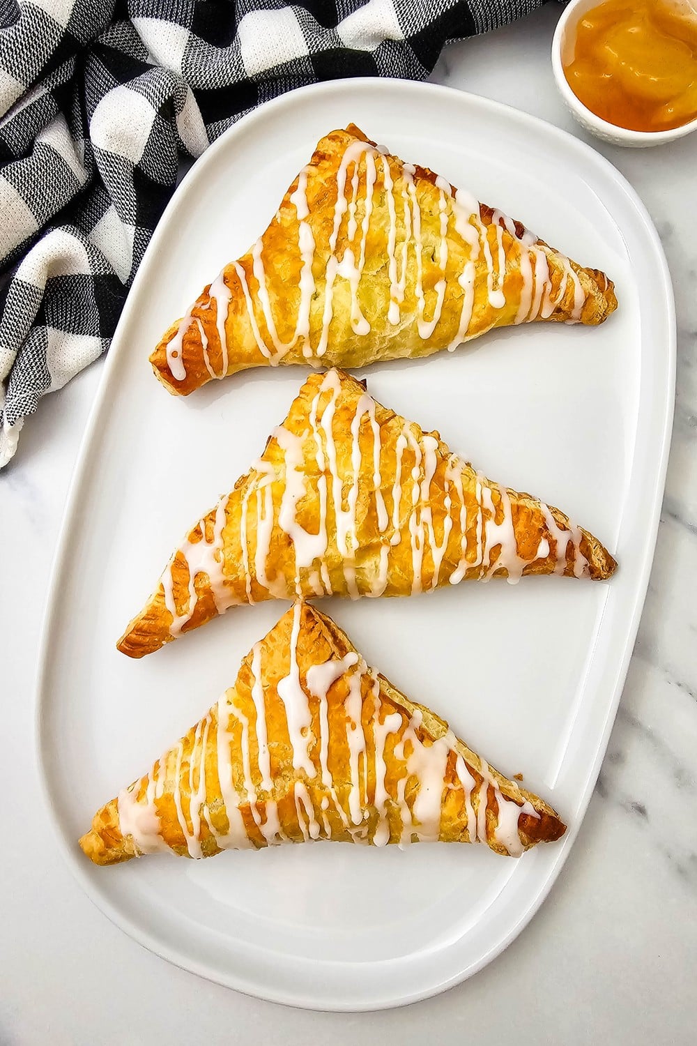 Overhead view of a glazed apple turnover on a white plate