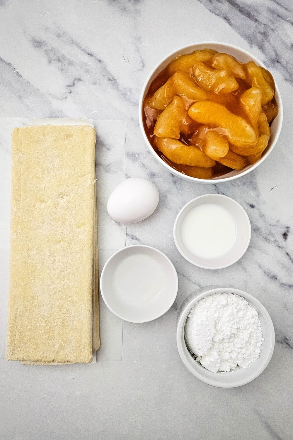 Apple turnover ingredients: puff pastry, apple pie filling, egg, powdered sugar and milk